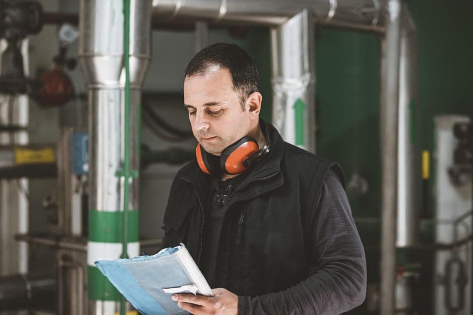 Worker on shop floor assessing and documenting