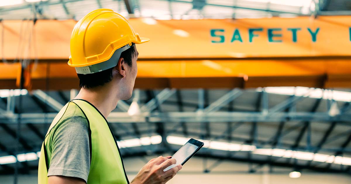 Manufacturing plant floor worker conducts a safety inspection using a tablet